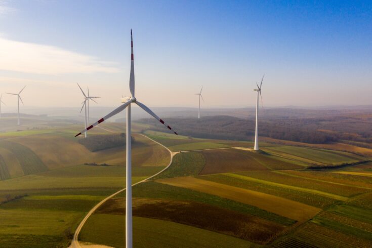 Aerial view of wind turbine under moody sky on fields