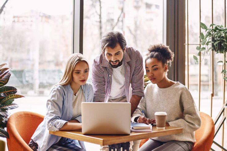 Diverse group of people together looking at a laptop