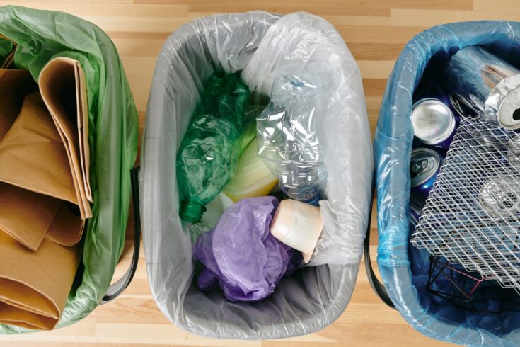 A group of various kind of trash in plastic bags on wooden table