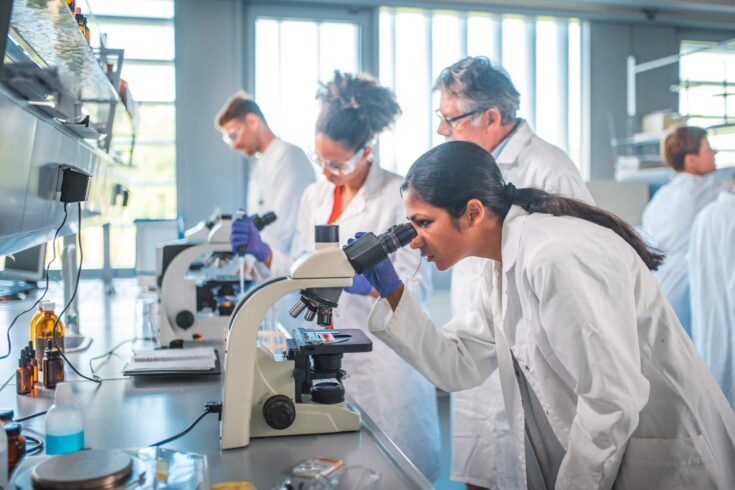 Female scientist using microscope in laboratory.