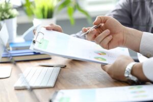 Close up shot of a man holding a clipboard with charts and a pen