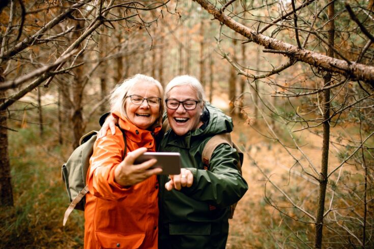 Close up of two female seniors taking a selfie while hiking in the forest