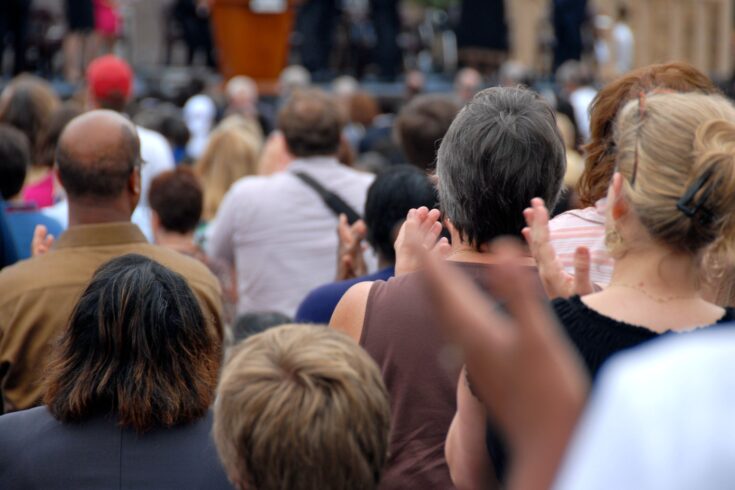 Multi-ethnic crowd applauds the speaker.