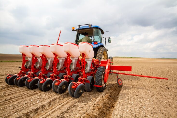 Tractor sowing seed to field at spring time