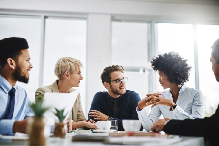 Cropped shot of a diverse group of businesspeople sitting together and having a meeting in the office