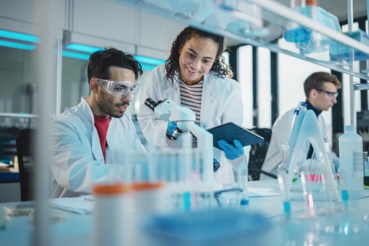 Young scientists using microscope and digital tablet in an advanced research laboratory