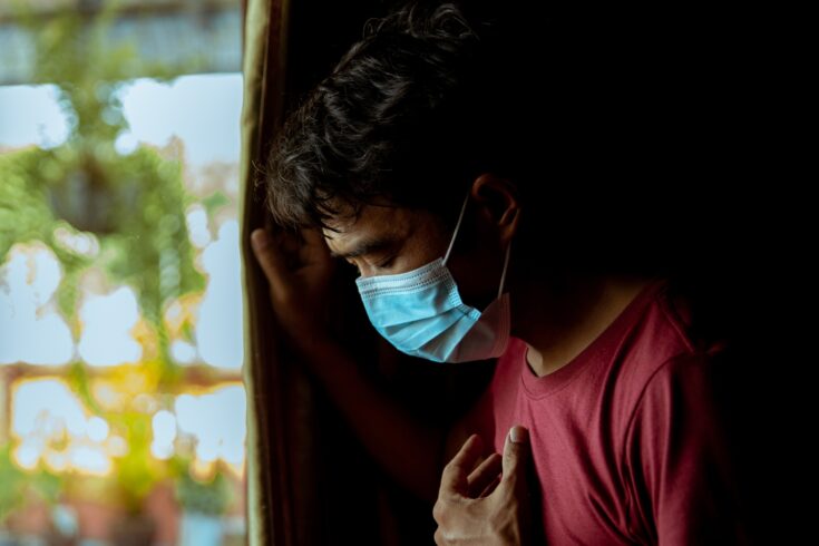 Asian man wearing a mask has difficulty breathing and has a side effect after suffering from COVID-19