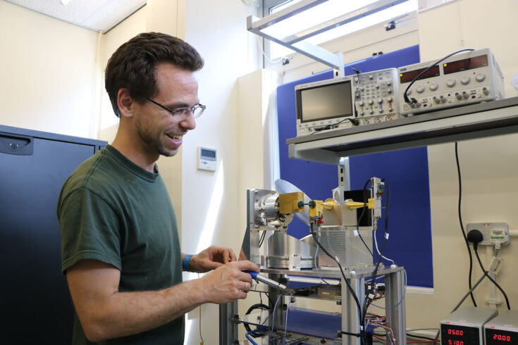 A man working on the Hyperspectral Microwave Sounder (HYMS) instrument.
