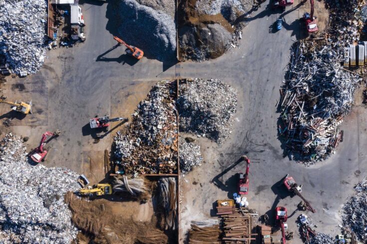 Aerial photograph of waste disposal site with large amounts of iron scraps and many excavator cars in operation.