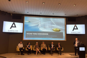 Panel discussion on stage at Alderley Park conference room.