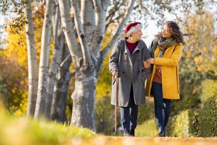 Woman with grandmother walking in park in autumn