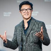 Lewis Hou standing with a headset mic and arms apart, giving a talk
