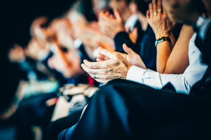 Group of businesspeople sitting in a row and applauding