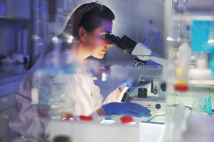 Female scientist working with microscope and pathogen samples