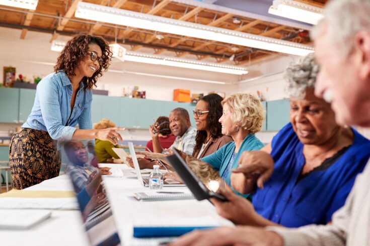 Group of retired seniors attending class in community centre with teacher