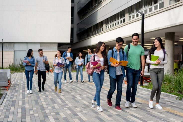 Young latin american students leaving the university campus after a day of class smiling