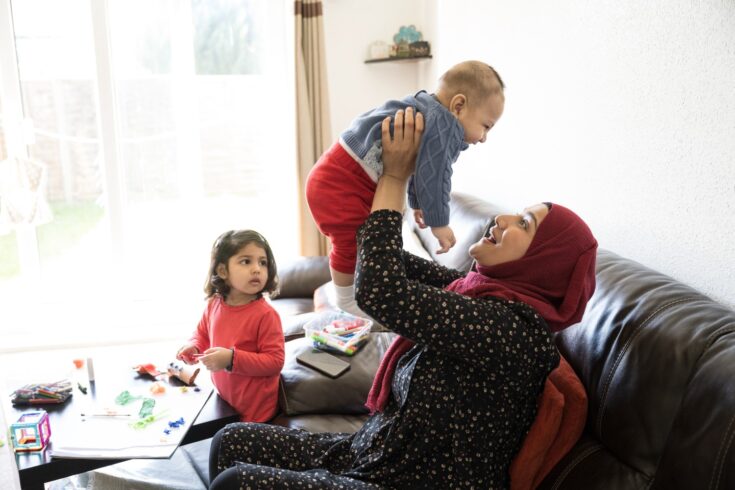 Early 30s mother playing with her baby son at home