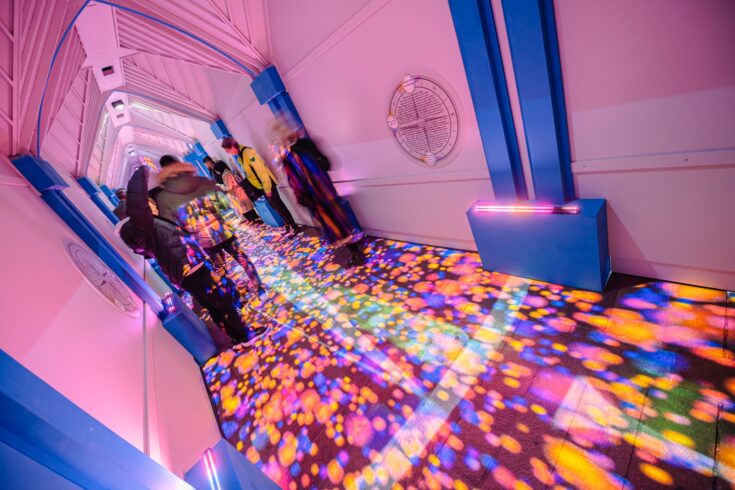 A pink lit corridor with multi-coloured floor projection in the UKRI-supported Compass art installation, British Science Festival 2022