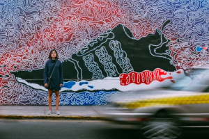 Woman on pavement in front of street art on wall