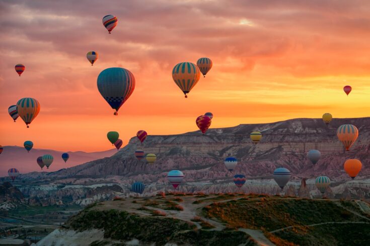 Hot air balloons flying tour over Mountains landscape spring sunrice Cappadocia, Goreme Open Air Museum National Park, Turkey