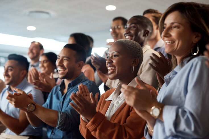 Shot of a group of young businesspeople clapping during a conference in a modern office