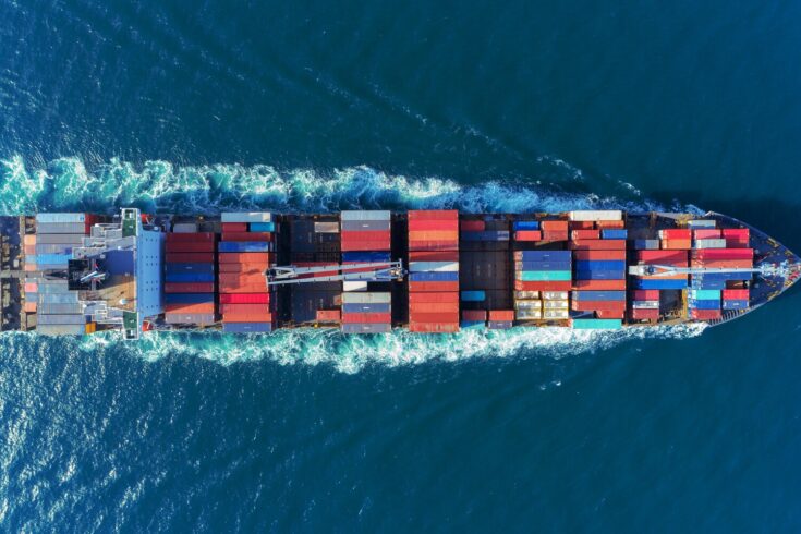 Aerial view Top speed with beautiful wave of container ship full load container with crane loading container for logistics import export or transportation concept background.