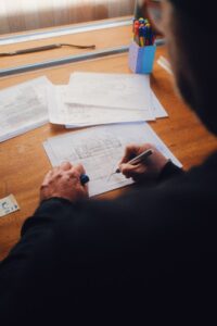 Architect adding to a technical drawing using blue pen on tracing paper.