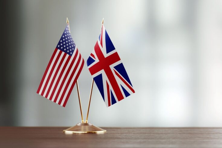 American and British flag pair on desk over defocused background