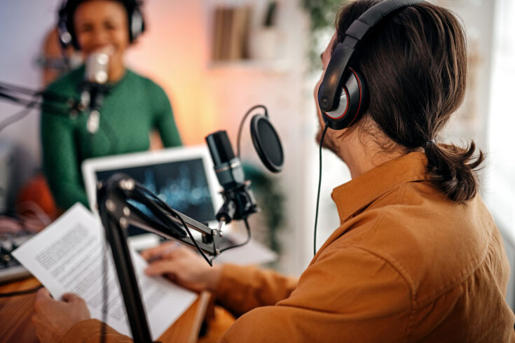Back view of a young man recording a podcast on interview with a women in the studio.