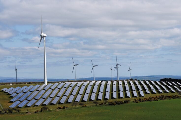 Renewable energy farm with solar panels and wind turbines.