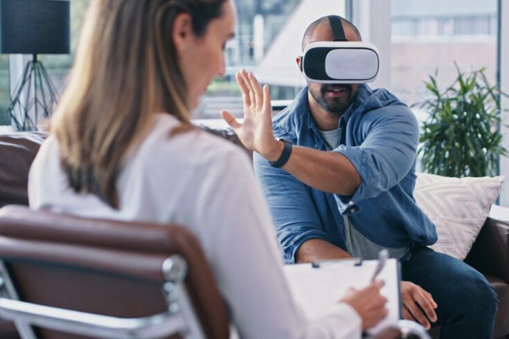 Cropped shot of a young man wearing a vr headset while sitting in session with his female therapist