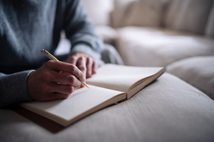 Cropped hand of man writing in notebook