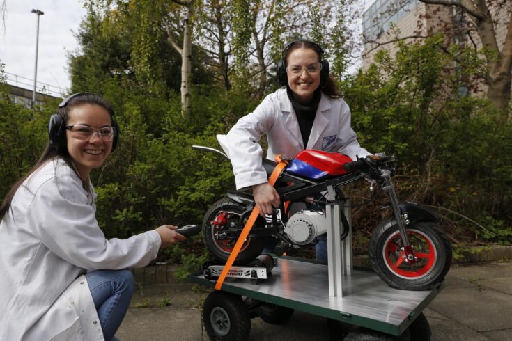 Winner of delivering zero emissions transport and mobility solutions. Two female researchers with a mini motorbike with an on-board carbon capture system.