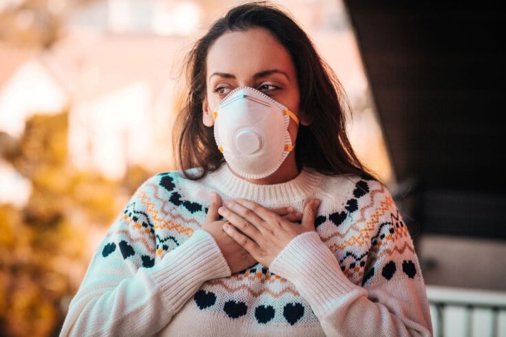 Woman wearing a respiratory mask out in a polluted city