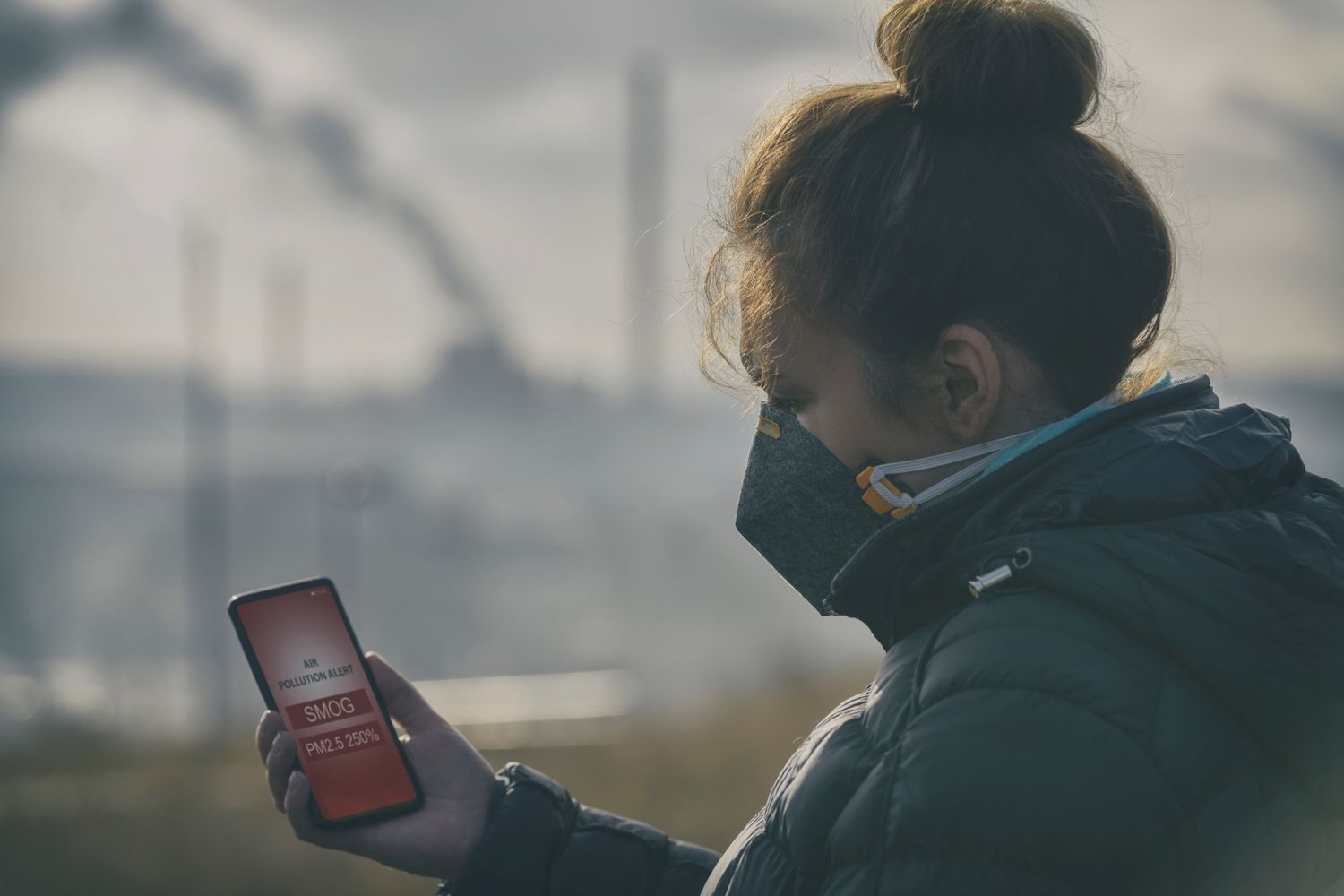 Woman wearing an anti-smog face mask and checking current air pollution with smart phone app