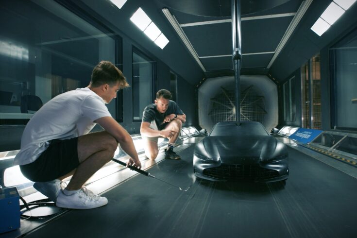 Two men working in a wind tunnel with a car