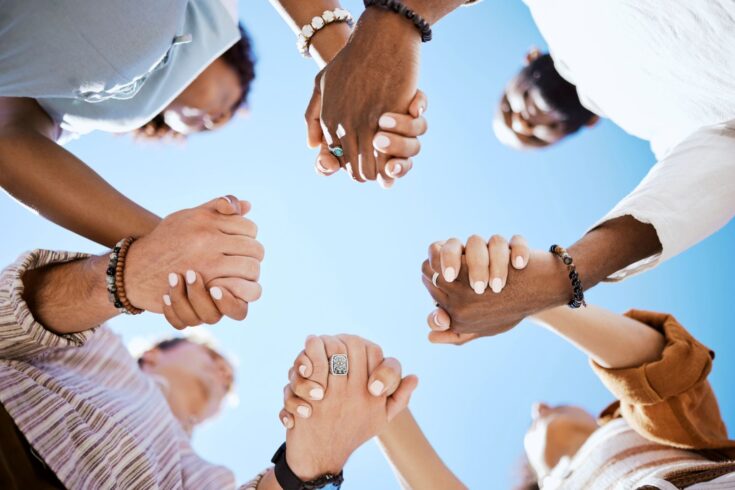 people holding hands against sky background.