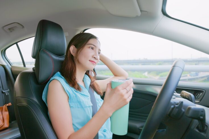 relaxed woman experiences riding autonomous self driving car and holding a hot flask
