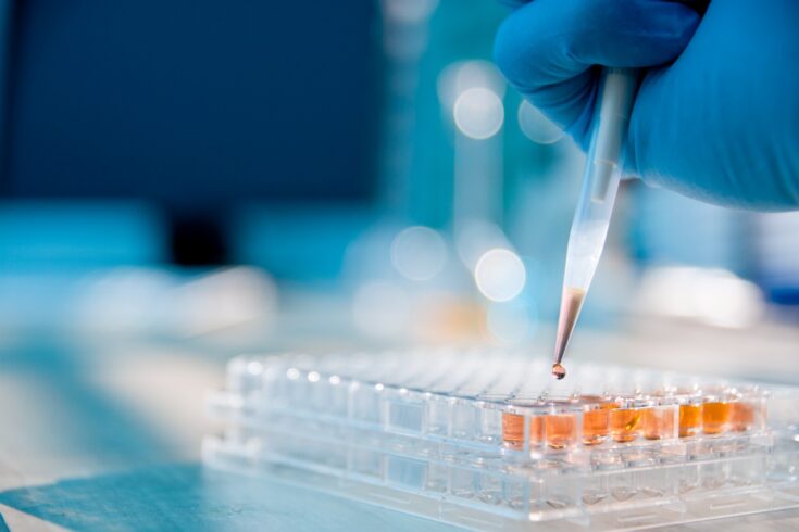 Lab technician injecting liquid into a microtiter plate