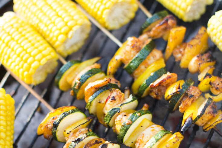 Food on an outdoor barbeque with corn cobs.