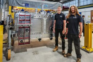 Two men stood in front of large steel piece of lab equipment