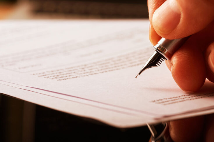 A hand holding a fountain pen and about to sign a letter.