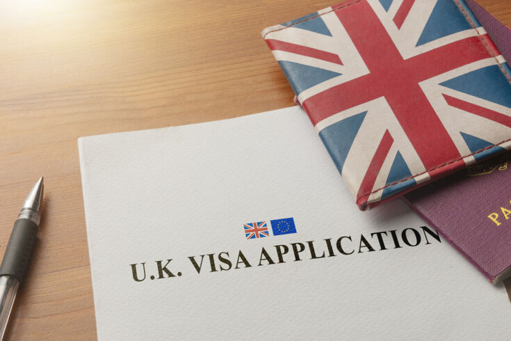 Visa application on desktop with passport and union jack wallet.
