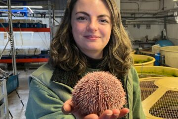 A girl smiling and holding a sea urchin