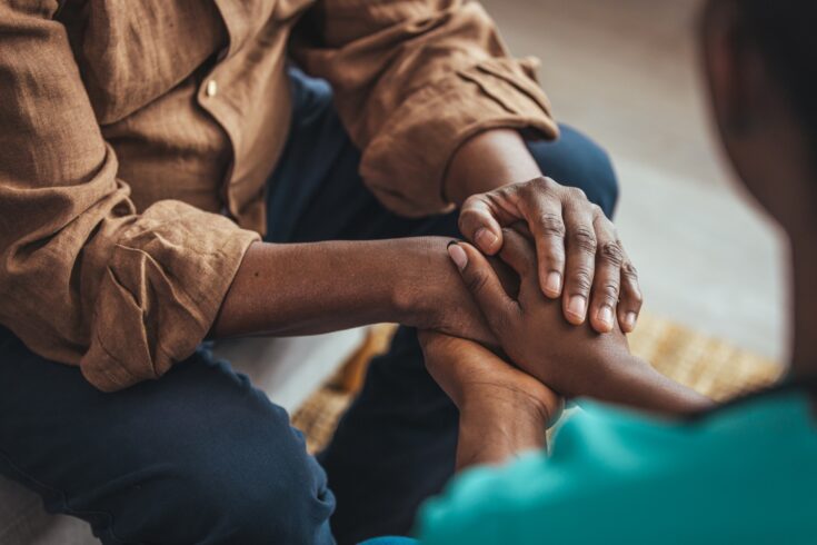 Close up of a carer holding a man's hands