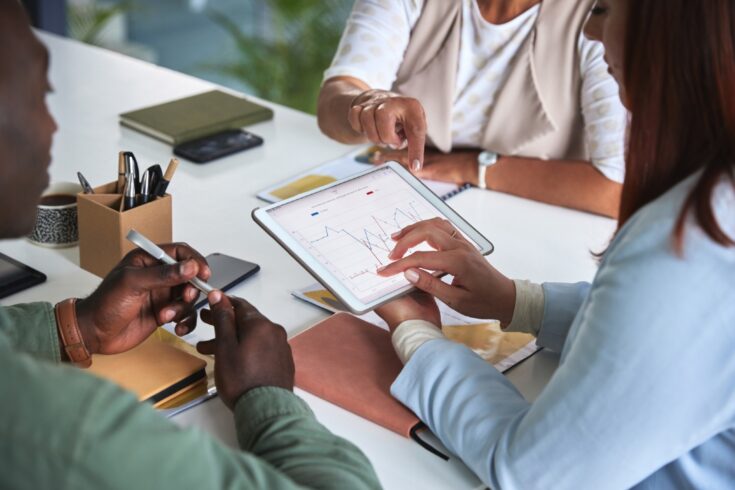 People studying a chart on a tablet in a meeting.