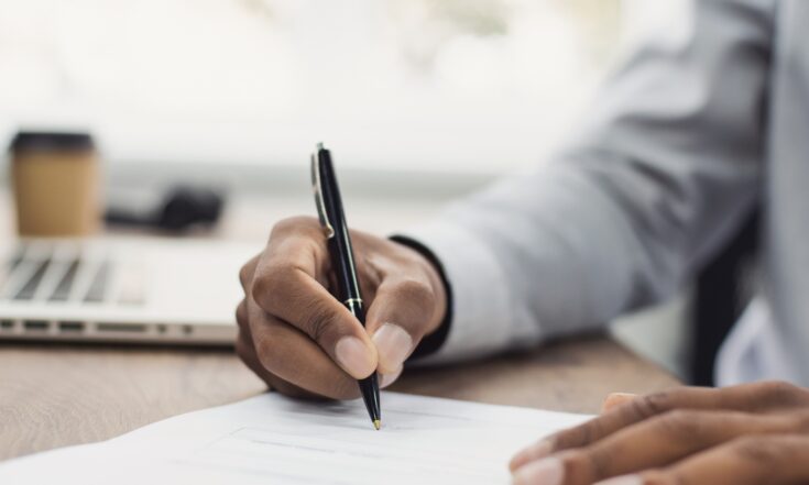 Close up of a man signing a document.