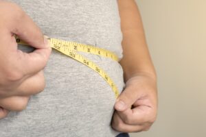 Man holding measuring tape around his waist