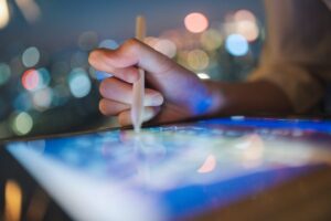 Close-up of a hand pointing at a tablet with a stylus.