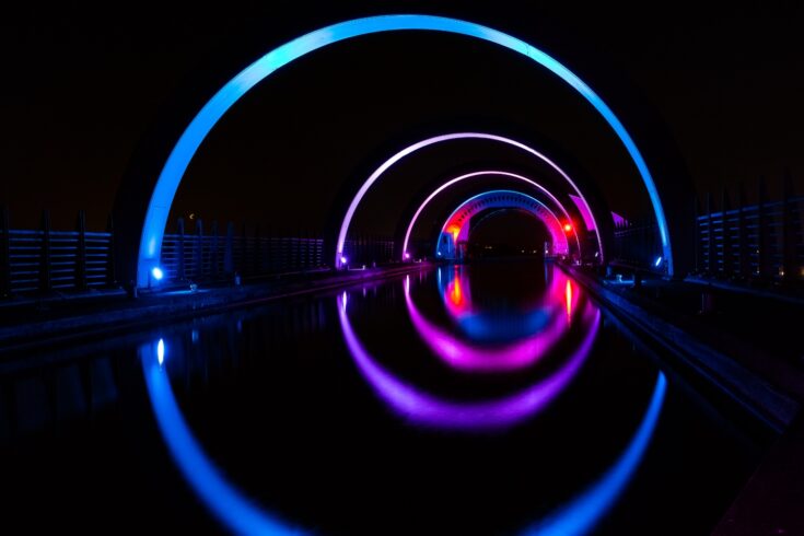 Futuristic purple neon lights reflecting on water at night.